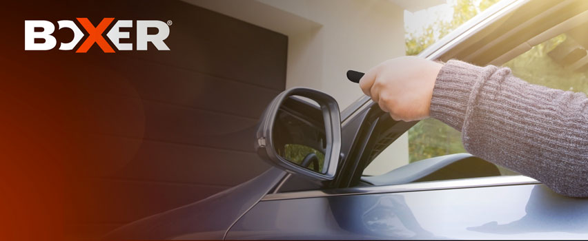 Boxer garagedeuropener – persoon opent automatische garagedeur met afstandsbediening vanuit auto