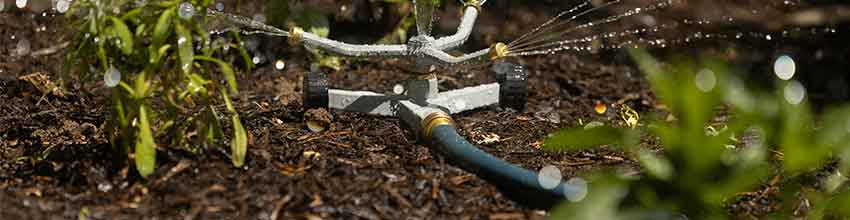 Sprinklers in de tuin sproeien water in drie verschillende richtingen.