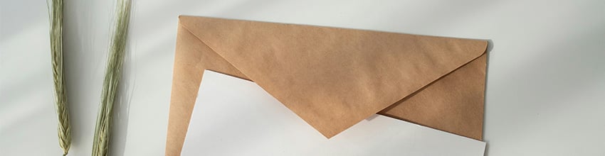 Wit kaartje en bruine envelop liggen op tafel.