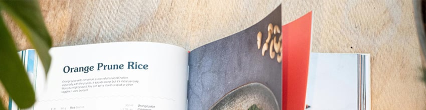 Het kookboek ligt op tafel en wordt doorgebladerd.