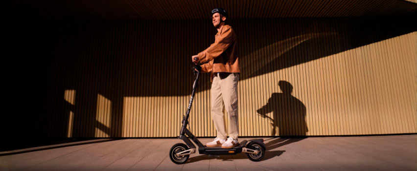 Man rijdt op Navee ST3 Pro e-step met stevige banden en premium design in avondlicht