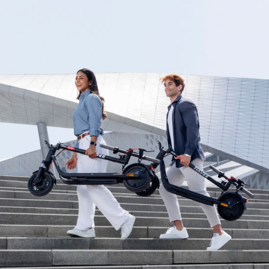 Jong stel draagt opvouwbare Navee V e-steps de trap af – compact en gemakkelijk te vervoeren