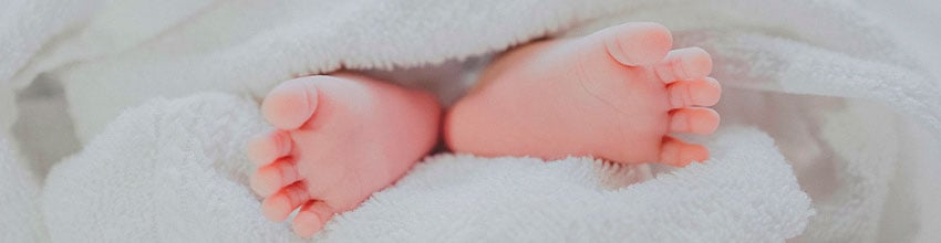 Zachte babyvoetjes in een witte handdoek, symbool voor zorgzame cadeau-ideeën voor baby's.