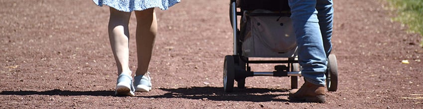 Ouders met een kinderwagen tijdens een wandeling, geven inspiratie voor praktische en persoonlijke cadeaus voor kersverse ouders.