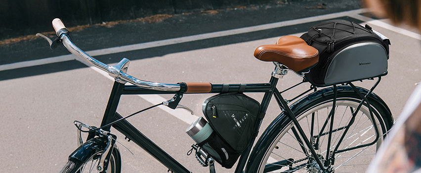 Vintage fiets met Wozinsky zadeltassen en frametas geparkeerd op zonnige straat – fietsaccessoires voor tochten
