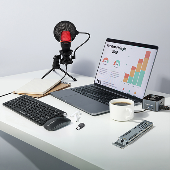 Wozinsky computerapparatuur met toetsenbord, muis, microfoon, laptopstandaard en koffiekopje op licht bureau