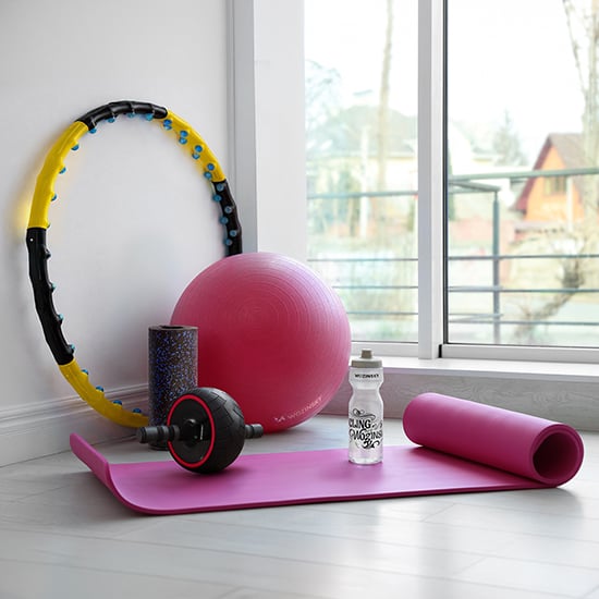 Wozinsky sport- en fitnessuitrusting met roze yogamat, bal, hoelahoep, foamroller en drinkfles bij het raam